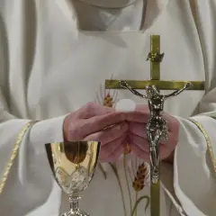 Ksiądz trzyma hostię i krzyż. Złoty kielich stoi obok. Zastanawiasz się, ile trwa msza?