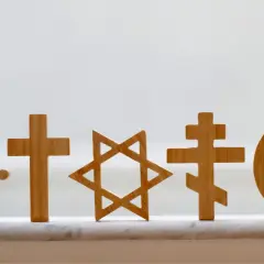 Drewniane symbole religijne: koło Dharmy, krzyże, Gwiazda Dawida, półksiężyc z gwiazdą. Pokazują różnorodność wierzeń, jak w Bangladeszu religia.