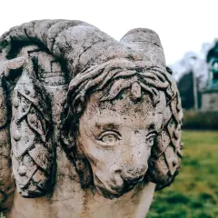 Kamienna rzeźba z wyrytymi imionami demonów, przypominająca lwa z rogami.