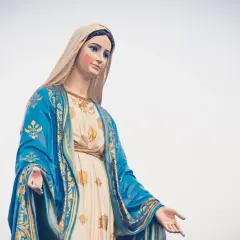 Posąg Matki Boskiej w niebieskim płaszczu ze złotymi zdobieniami, jakby witała rycerzy Maryi.