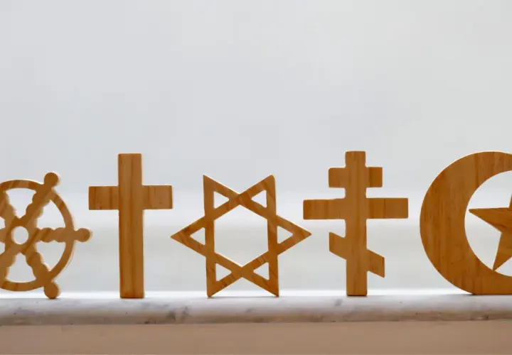 Drewniane symbole religijne: koło Dharmy, krzyże, Gwiazda Dawida, półksiężyc z gwiazdą. Pokazują różnorodność wierzeń, jak w Bangladeszu religia.