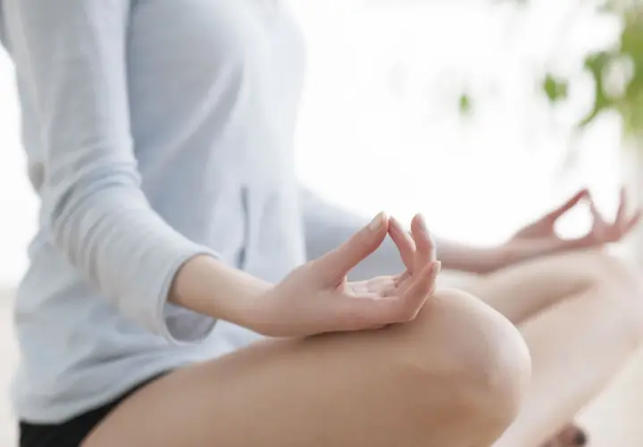 Kobieta w pozycji lotosu, dłonie w mudrze. Praktyka medytacji transcendentalnej dla spokoju umysłu.
