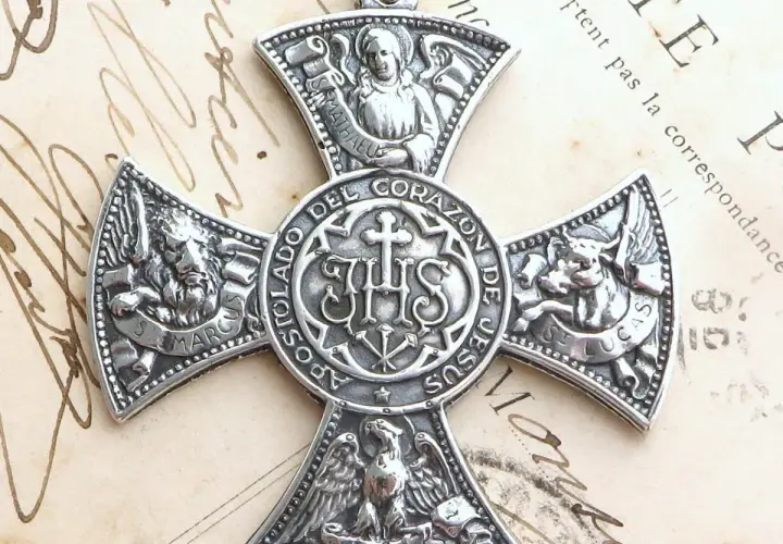Srebrny medalion z symbolem IHS i symbolami ewangelistów: lew (św. Marek), anioł (św. Mateusz), wół (św. Łukasz) i orzeł (św. Jan).