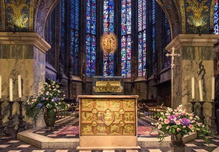 Wnętrze katedry z witrażami, ołtarzem i kwiatami. W tle złota monstrancja, przypominająca o tęsknocie z psalm 137 tekst.