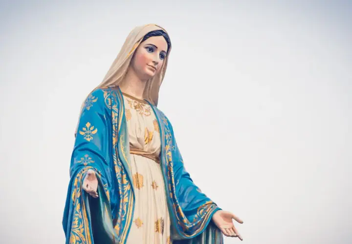 Posąg Matki Boskiej w niebieskim płaszczu ze złotymi zdobieniami, jakby witała rycerzy Maryi.