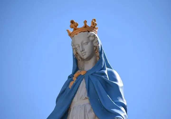 Figura Matki Bożej z koroną na głowie, w niebieskim płaszczu. Jej postawa przypomina błogosławieństwo z Psalmu 112.