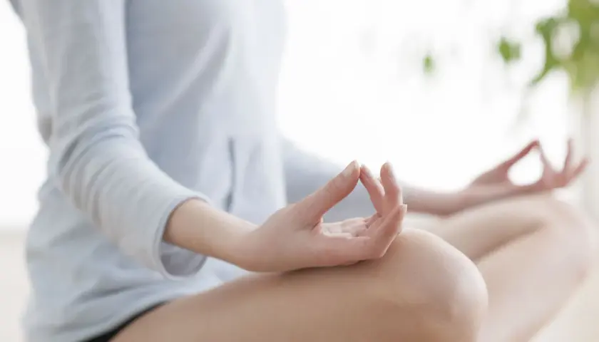 Kobieta w pozycji lotosu, dłonie w mudrze. Praktyka medytacji transcendentalnej dla spokoju umysłu.