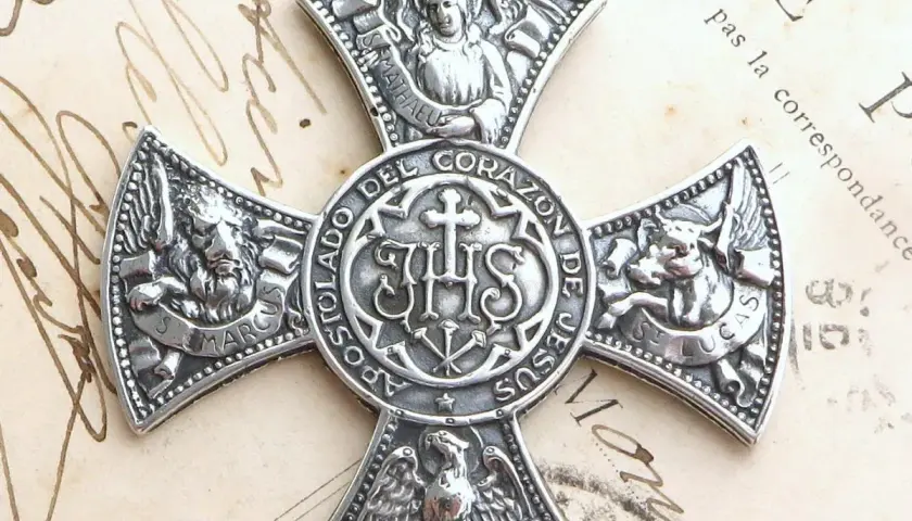 Srebrny medalion z symbolem IHS i symbolami ewangelistów: lew (św. Marek), anioł (św. Mateusz), wół (św. Łukasz) i orzeł (św. Jan).