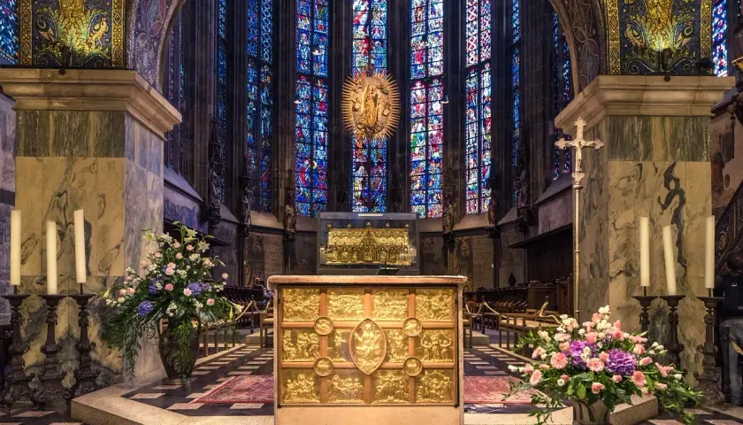 Wnętrze katedry z witrażami, ołtarzem i kwiatami. W tle złota monstrancja, przypominająca o tęsknocie z psalm 137 tekst.