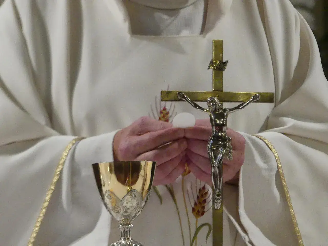 Ksiądz trzyma hostię i krzyż. Złoty kielich stoi obok. Zastanawiasz się, ile trwa msza?