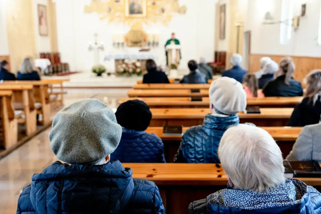 Ludzie siedzą w kościele, słuchając kazania. 1 maja święto kościelne, wierni uczestniczą w nabożeństwie.